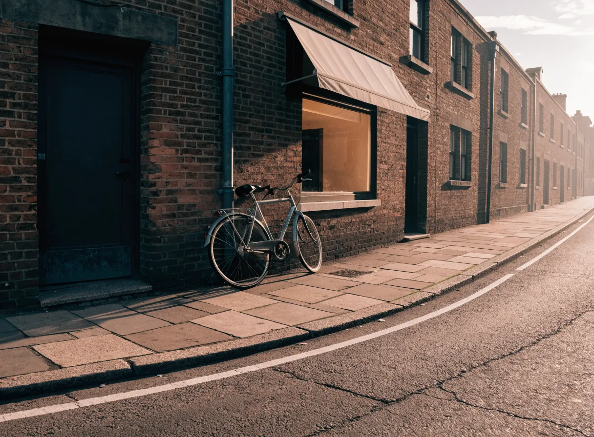 A quiet brick street in Shoreditch in the morning, with a warmly lit shopfront and a bicycle leaning on the wall